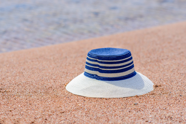Trendy sunhat lying on beach sand - Foto, afbeelding