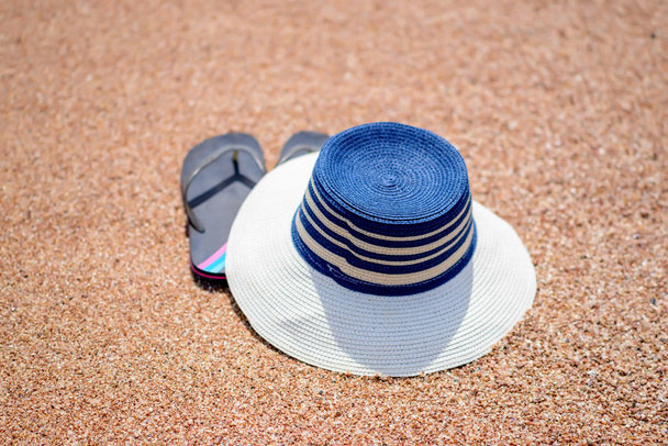 Trendikäs auringonhattu ja ranta tangat hiekalla
 - Valokuva, kuva
