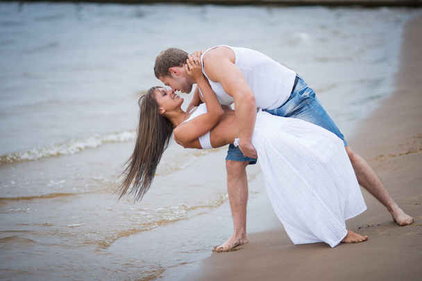 Gelukkige jonge paar verliefd wandelen op het strand - Foto, afbeelding