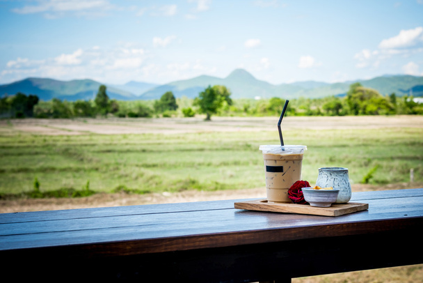 Kawa na zimno na drewniany stół i tło krajobraz. - Zdjęcie, obraz