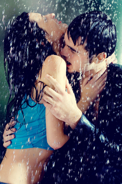 Young couple hugging and kissing under a rain - Fotó, kép