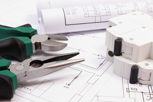 Las herramientas de trabajo, el fusible eléctrico y los rollos de los diagramas sobre la construcción el dibujo de la casa
 - Foto, Imagen