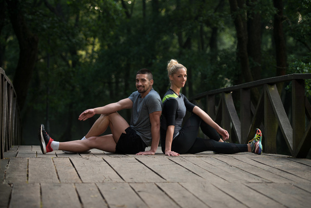 Young Couple Stretching Before Running In Wooded Forest - Foto, Imagen