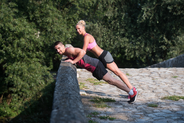Young Couple Doing Pushups Outdoor - 写真・画像