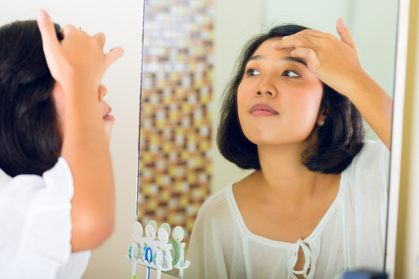 Mulher asiática descobrindo uma espinha na cara
 - Foto, Imagem