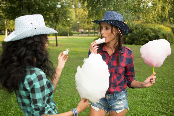 beautiful girls in cowboy hats eating cotton candy - Фото, изображение