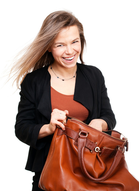 Young smiling woman seeking in big brown handbag - Foto, imagen