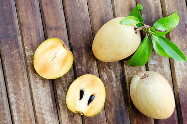 Fresh sweet sapodilla fruit with leaves on wooden background - Foto, immagini