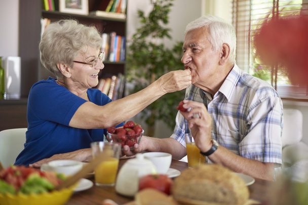 Vanhempi nainen ruokkii miehensä mansikoilla
 - Valokuva, kuva