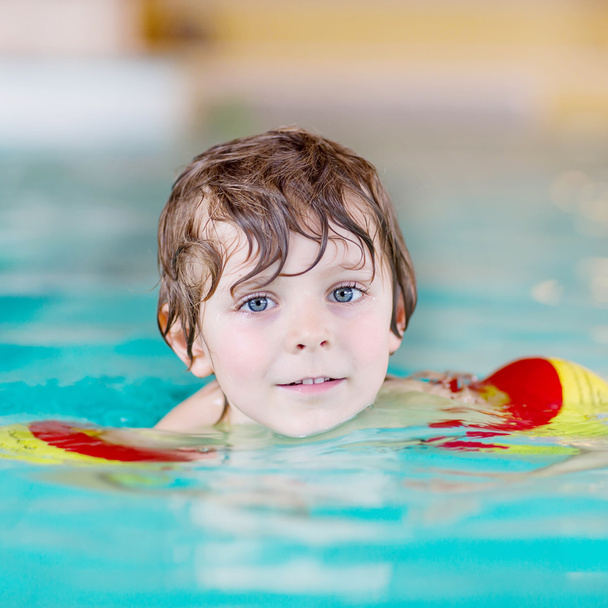 маленький мальчик с пловцами учится плавать в закрытом бассейне
 - Фото, изображение