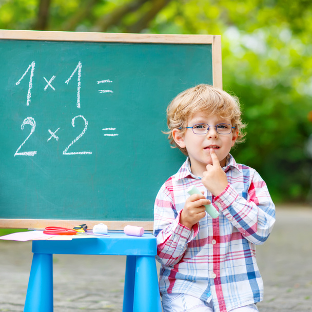Χαριτωμένο μικρό αγόρι παιδί με τα γυαλιά στο μαυροπίνακα εξάσκηση mathem - Φωτογραφία, εικόνα
