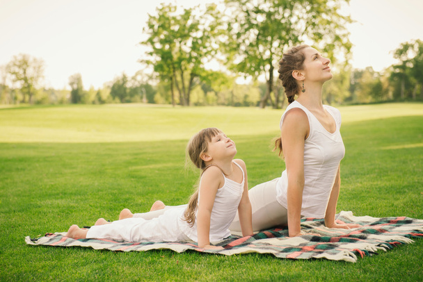 Moeder met dochter doen yoga oefening - Foto, afbeelding