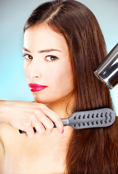 Woman with long hair holding blow dryer and comb - Foto, Bild
