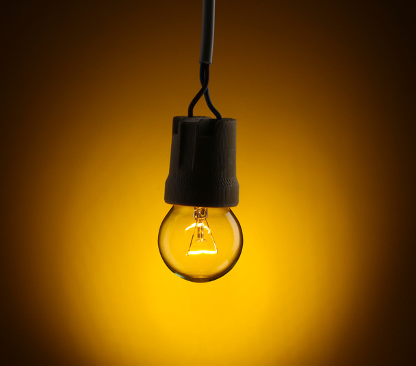 黄色の背景に点灯している電球 - 写真・画像