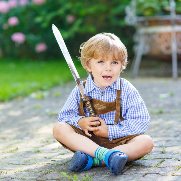 Portrait of little blond kid boy with toy sword - Fotó, kép