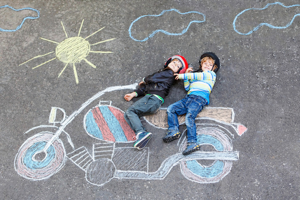 Two kid boys in helmet with motorcycle picture drawing with colo - Photo, Image