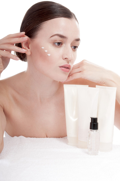 Sensual woman applying cosmetic cream treatment on her face - Foto, Imagen