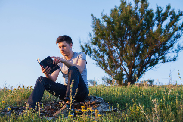 ο άνθρωπος που κάθεται πάνω σε ένα λόφο και διαβάζοντας ένα βιβλίο - Φωτογραφία, εικόνα