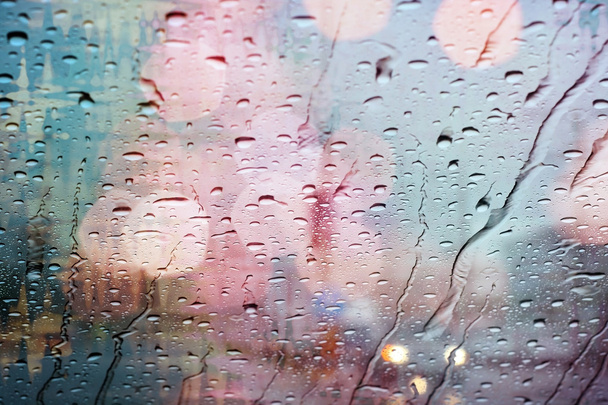 Weergave van de weg door auto raam met regendruppels en lichte bokeh. - Foto, afbeelding