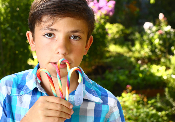  jongen met regenboog snoep stokken dicht omhoog portret - Foto, afbeelding