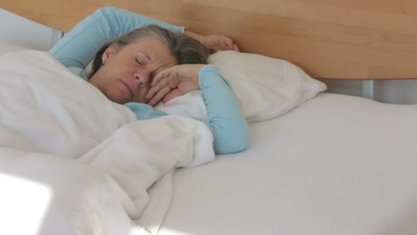 落ち着きのないベッドで寝ている彼女の 50 代女性 - 映像、動画