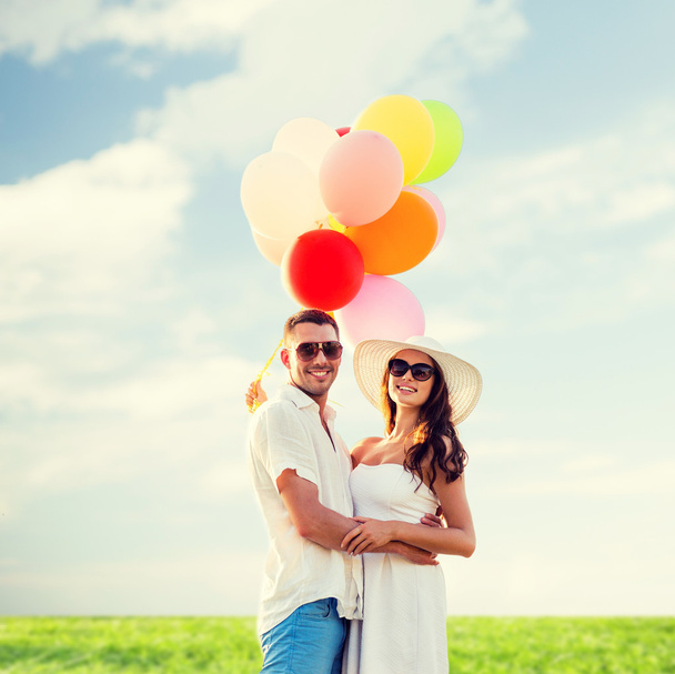 smiling couple with air balloons outdoors - Fotó, kép