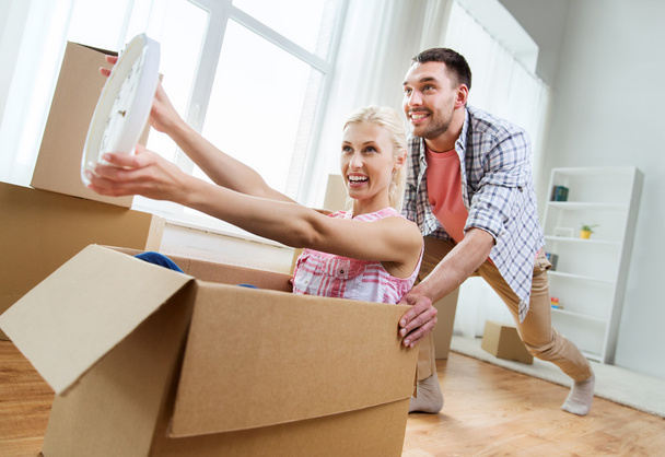 couple with cardboard boxes having fun at new home - Foto, Bild
