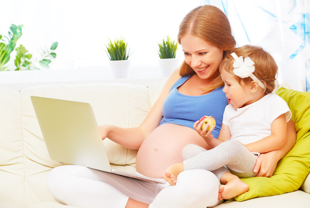 Ευτυχισμένη οικογενειακή έγκυος γυναίκα και το παιδί με ένα φορητό υπολογιστή στο σπίτι - Φωτογραφία, εικόνα