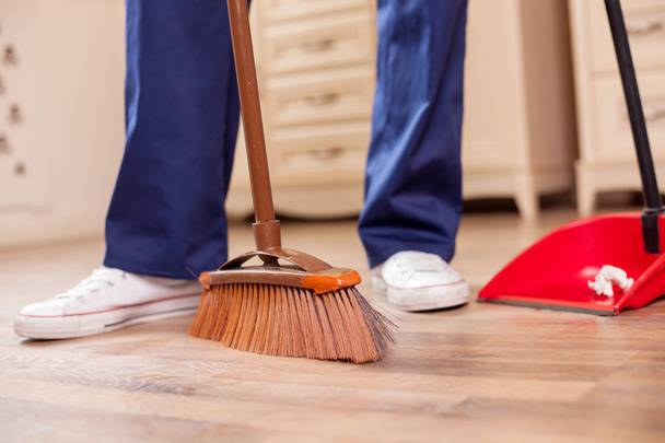 Skilled young male cleaner is cleaning floor in room - 写真・画像