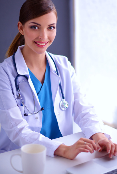 Female doctor working sitting on gray  background - Φωτογραφία, εικόνα