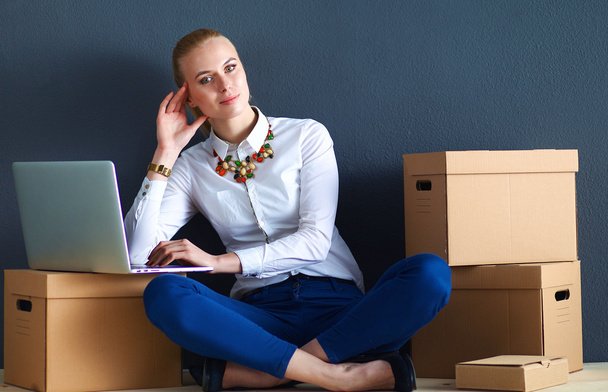 Woman sitting on the floor near a boxes  with laptop  - Photo, image