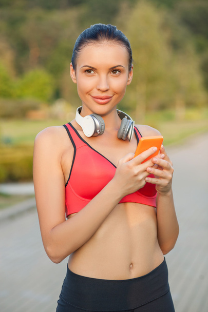 Cheerful young woman is running with headphones - Zdjęcie, obraz