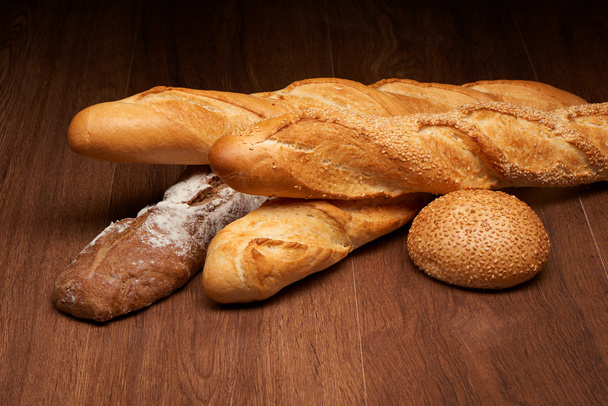 Panes de baguette diferentes y pan en mesa de madera oscura
 - Foto, Imagen