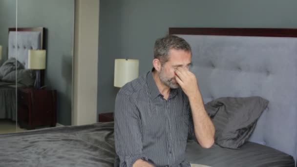 man in shirt sitting on a bed and looking distressed - Záběry, video