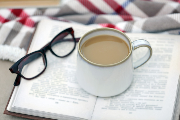 Cup of coffee with book on sofa in living room - Φωτογραφία, εικόνα