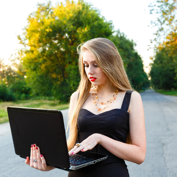 joven hermosa mujer sonriente con un ordenador portátil en el camino
 - Foto, imagen