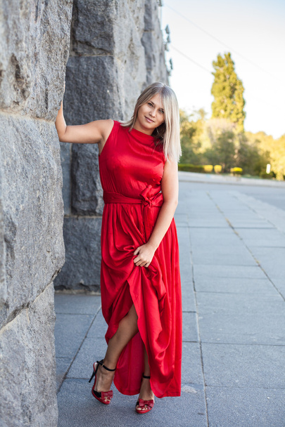 beautiful girl posing in a red evening dress in the park outdoor - Photo, image