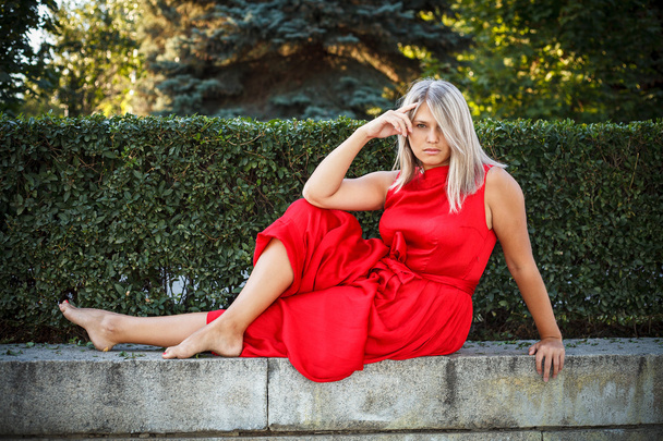 beautiful girl posing in a red evening dress in the park outdoor - Photo, image