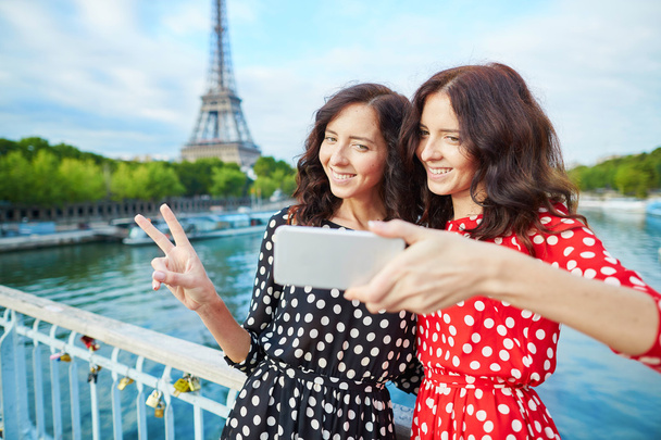 Beautiful twin sisters taking selfie in front of Eiffel Tower - Foto, Imagen