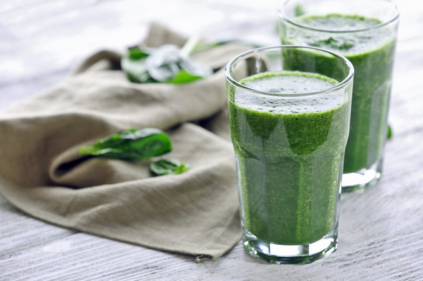 Glasses of spinach juice with napkin on wooden table, closeup - Foto, immagini