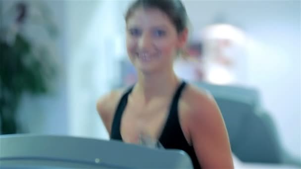 Молодая милая девушка бежит в спортзале улыбаясь и глядя в камеру
 - Кадры, видео