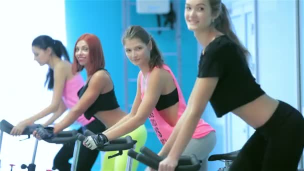 Graceful sexy girl pedaling and looking at the camera on a stationary bike - 映像、動画