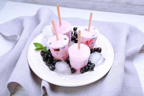 Sweet ice cream with black currants in white plate on grey napkin, closeup - Foto, afbeelding