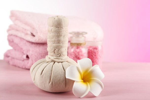 Massagetaschen mit Wellness-Behandlung und Blumen auf Holztisch, auf hellem Hintergrund - Foto, Bild