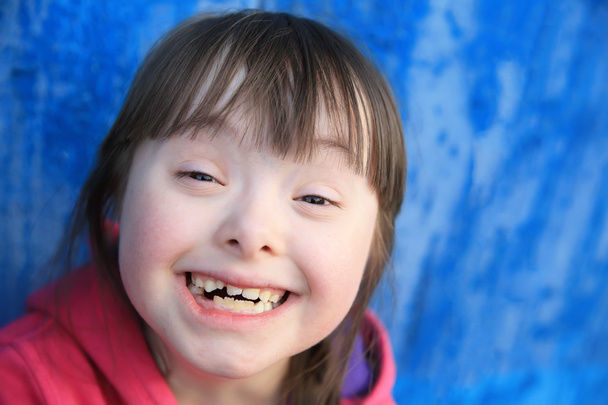 Young girl smiling on background of the blue wall. - Foto, imagen
