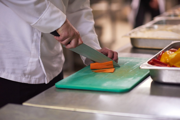 chef in hotel kitchen slicing vegetables with knife - Foto, Imagem