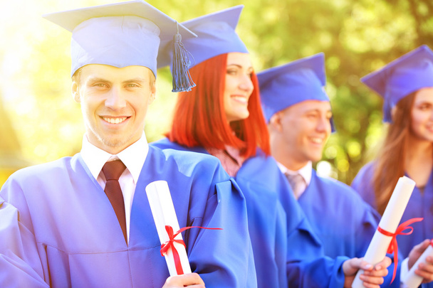 Estudantes graduados em chapéus e vestidos de graduação, ao ar livre
 - Foto, Imagem