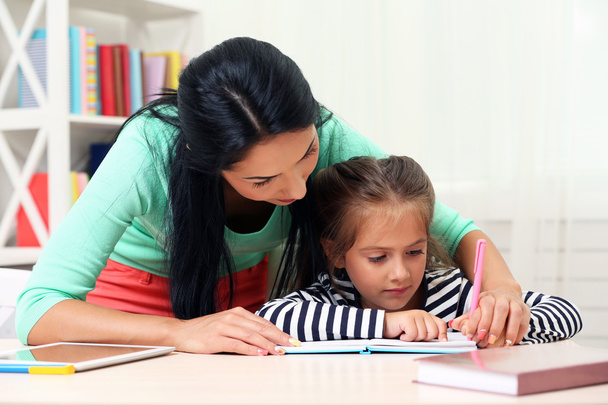 School girl doing homework with mother  - Foto, afbeelding