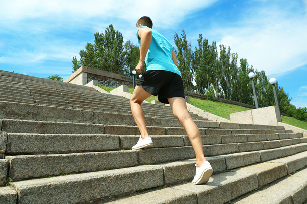 Young man jogging at stairs outdoors - Фото, зображення