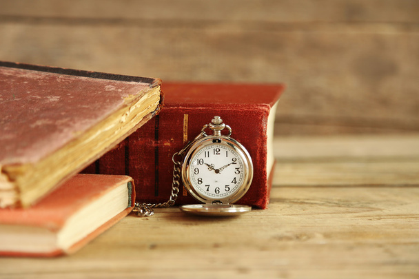 Pocket clock and vintage books, on rustic wooden background - Фото, изображение